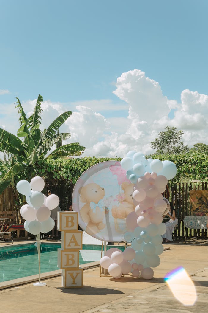 Pastel balloons and baby blocks by a pool, set for a gender reveal in Presidente Prudente, Brazil.
